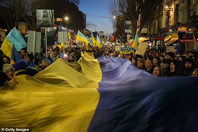 Members of the Ukrainian community hold a large flag as they take part in a rally outside the Russian Embassy in London to mark the first anniversary of Russia's invasion of Ukraine